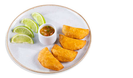 Empanadas with spicy sauce and lemon wedges on a plate, top viewの写真素材