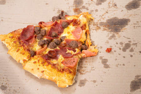 Last piece of pizza in the cardboard box on the tableの写真素材