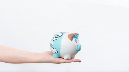 female hand holding a piggy bank on white backgroundの写真素材