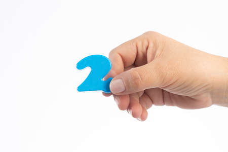 Woman's hand holding plastic number 2 symbol, close up image
