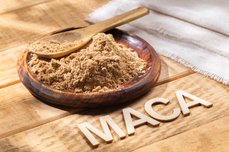 Maca powder, in wooden bowl on the table, nutritional substance from Peru.