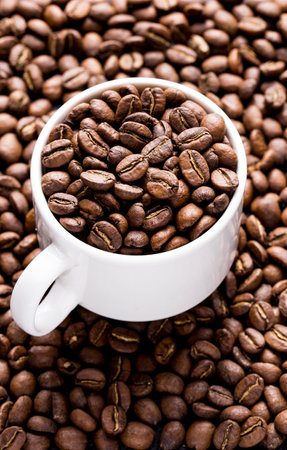 Roasted coffee beans in a cup, on dark background, close-up image, space for textの写真素材