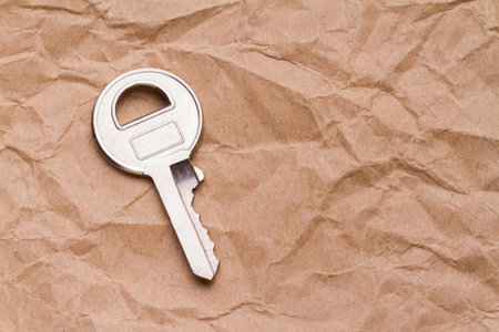 small steel key on crumpled paper background, space for textの写真素材