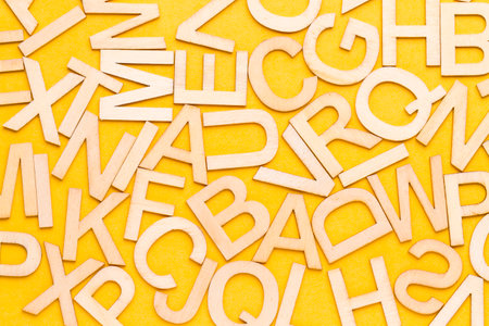 Set of letters of the alphabet in disorder, on yellow background, top viewの写真素材