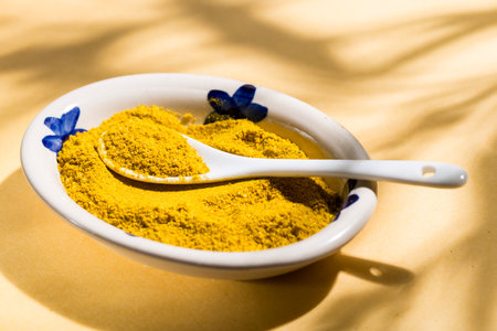 Yellow Comfort: Curry in Ceramic Bowl and Spoon with natural shadows, top viewの写真素材
