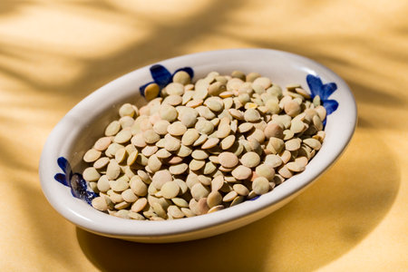 stack of lentils on a plate on a yellow background, view from aboveの写真素材