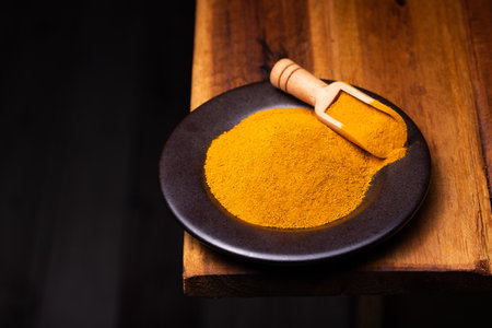 Turmeric Powder in a Wooden Spoon and Bowlの写真素材