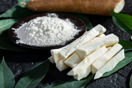 pile of cassava fruit and cassava flour on a background of rustic and dark texture (Manihot esculenta)の写真素材