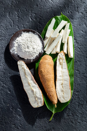 pile of cassava fruit and cassava flour on a background of rustic and dark texture (Manihot esculenta)の写真素材