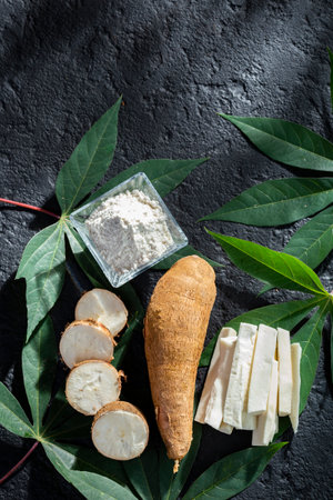 pile of cassava fruit and cassava flour on a background of rustic and dark texture (Manihot esculenta)の写真素材