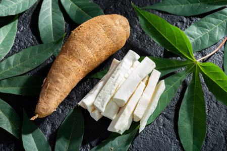 pile of cassava fruit and cassava flour on a background of rustic and dark texture (Manihot esculenta)の写真素材