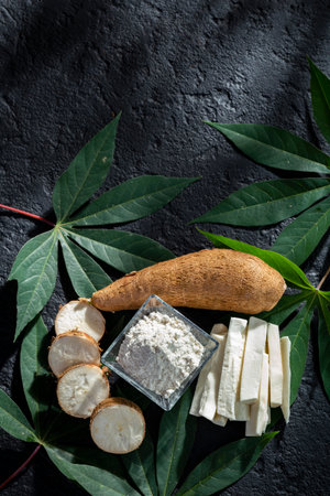 pile of cassava fruit and cassava flour on a background of rustic and dark texture (Manihot esculenta)の写真素材