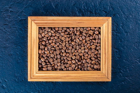 Roasted coffee beans in a wooden frame, on a blue backgroundの写真素材