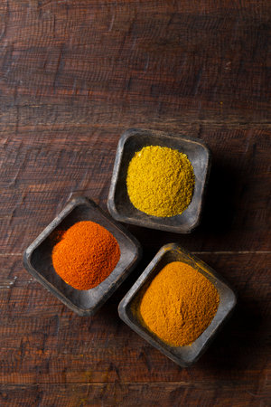 Turmeric, pepper and curry powder in container on wooden backgroundの写真素材
