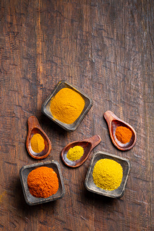 Turmeric, pepper and curry powder in container on wooden backgroundの写真素材