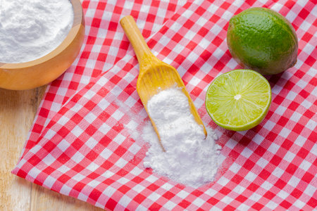 Baking soda in wooden bowl and lemons, on the tableの写真素材