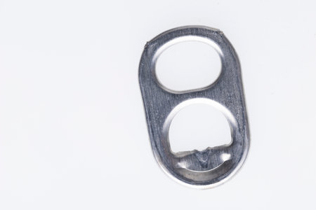 A closeup view of a silver aluminum can pull tab with a textured surface, isolated on a white background.の写真素材