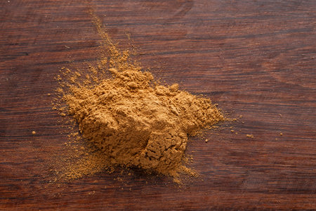 In the image you can see cinnamon powder on a rustic wooden surface