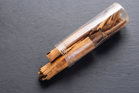several cinnamon sticks in a plastic container, on a gray slateの写真素材