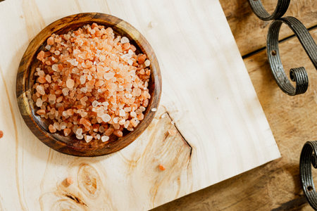 a pile of pink Himalayan salt is seen in the image on a wooden plate, on a rustic wooden surfaceの写真素材