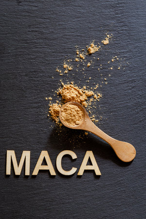 Maca powder in a wooden container on a gray slate surface