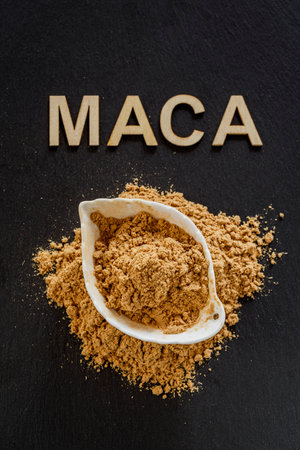 Maca powder in a wooden container on a gray slate surface
