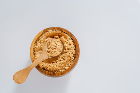 Medicinal maca powder in a wooden container on a gray slate surface