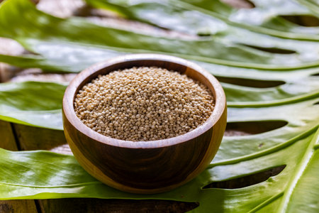 A pile of quinoa grains is seen in the image, in a wooden bowlの写真素材
