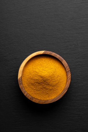 Wooden Spoons with Turmeric Powder on Slate Background â Natural Cooking Ingredientsの写真素材