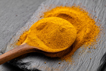Wooden Spoons with Turmeric Powder on Slate Background â Natural Cooking Ingredientsの写真素材