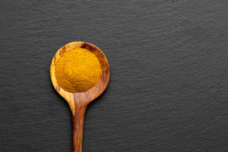 Wooden Spoons with Turmeric Powder on Slate Background â Natural Cooking Ingredientsの写真素材