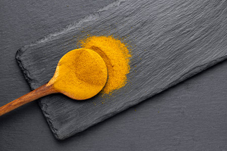Wooden Spoons with Turmeric Powder on Slate Background â€“ Natural Cooking Ingredients