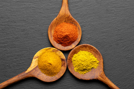 Colorful Spices on Wooden Spoons â Curry, Turmeric, and Paprika on Dark Slate Backgroundの写真素材