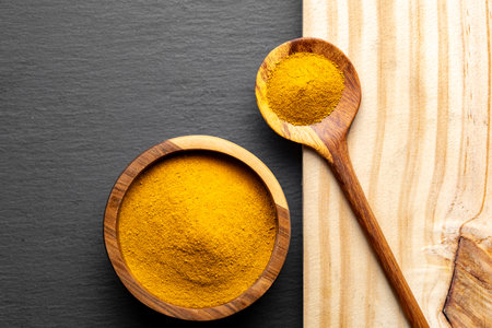 Wooden Spoons with Turmeric Powder on Slate Background â Natural Cooking Ingredientsの写真素材