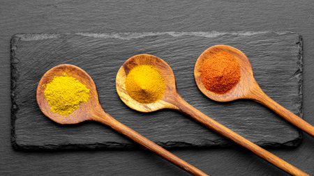 Colorful Spices on Wooden Spoons â Curry, Turmeric, and Paprika on Dark Slate Backgroundの写真素材