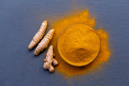 Fresh and ground turmeric root on a slate backgroundの写真素材