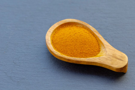 Fresh and ground turmeric root on a slate background