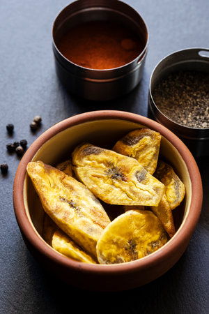 Crispy plantain chips in clay bowl on dark backgroundの写真素材