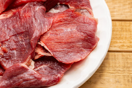Fresh Raw Beef Slices on White Plate on Wooden Tableの写真素材