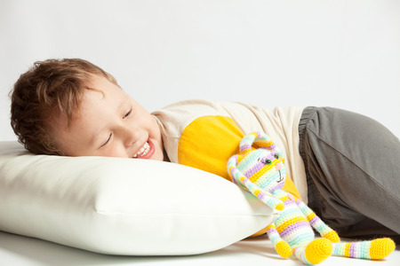 Boy lying on a white background with a knitted rabbit amigurumiの写真素材