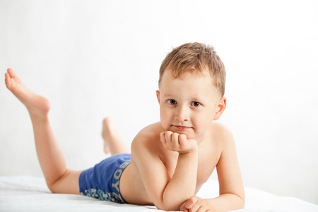 The boy in blue shorts lying on white backgroundの写真素材