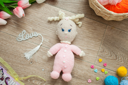 Crochet doll amigurumi doll was lying on the floor, and around tulips, buttons, hearts, basket balls and the word loveの写真素材