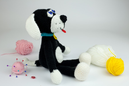 Knitted black and white dog amigurumi on white backgroundの写真素材
