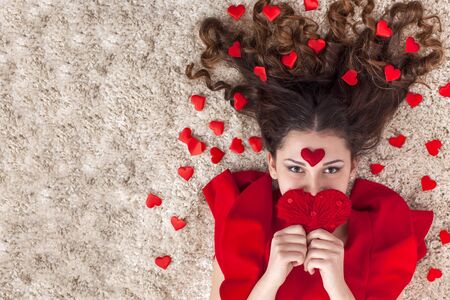 Portrait of young beautiful woman holding red heart-shaped symbolの写真素材