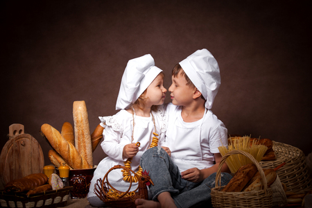 two baby boy and girl kissing, Fun posing while playing chefの写真素材