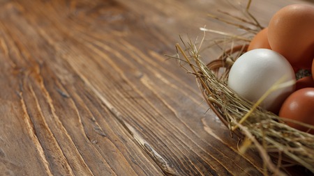 Fresh village chicken eggs on dark wooden background. Easter entourage. Basket or socketの写真素材