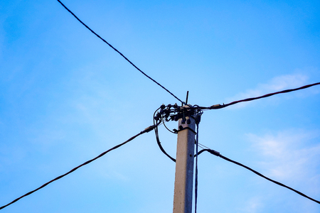 Cable on a concrete pole mounted modern insulated electric cable on an electric pole with a blue sky background. development in different directions, many ways, the connection into a single chain.の写真素材