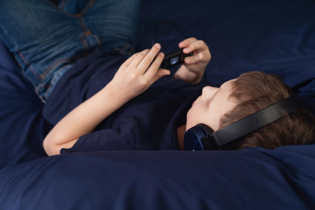 boy listening to music in headphones Lying in bedの写真素材