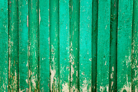 the old fence is a fragment of green color, the paint peels off from the wooden surfaceの写真素材
