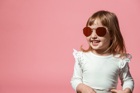 happy child in sunglasses on a pink coral background. with free text space.の写真素材
